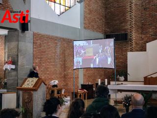 Le immagini dei funerali trasmesse nella chiesa parrocchiale di Nostra Signora di Lourdes ad Asti (Merphefoto)