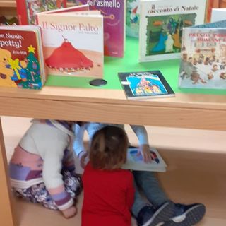 Alcuni bambini giocano sotto un tavolo della Biblioteca Monticone di Canelli