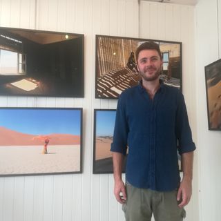 Il fotografo Gregory Pepper ritratto con alle spalle alcuni suoi scatti