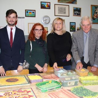 Angela Motta ritratta con i vertici Anffas nel laboratorio del mosaico