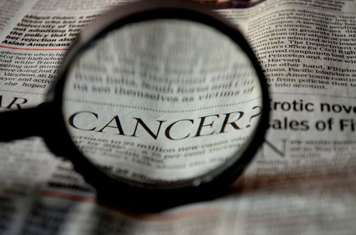 Lente di ingrandimento sulla parola cancro sulla pagina di un giornale