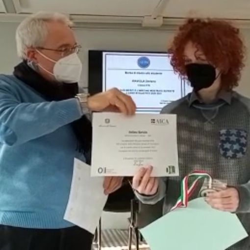 Il dirigente scolastico Franco Calcagno ritratto mentre consegna l'attestato ottenuto da Stefano Raviola, 5 AI dell'Artom, che ha ottenuto la medaglia di bronzo