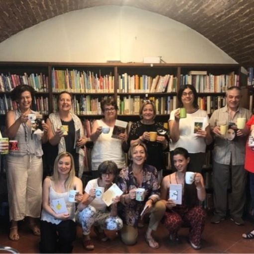 Il gruppo di partecipanti con libri e tazze in biblioteca