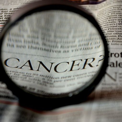 Lente di ingrandimento sulla parola cancro sulla pagina di un giornale