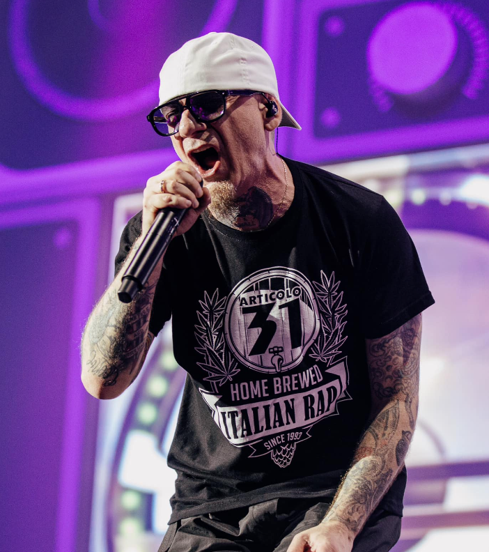 J-Ax ritratto sul palco durante un concerto degli Articolo 31 (immagine tratta dal profilo Facebook del duo artistico)