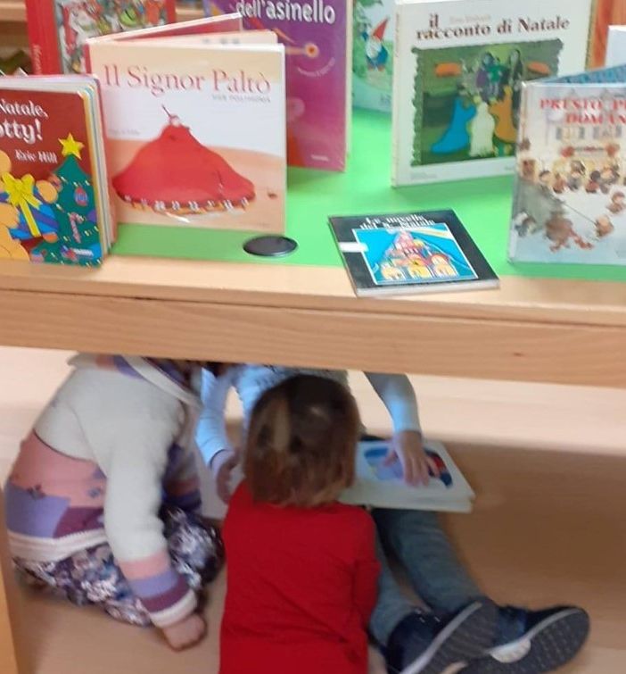 Alcuni bambini giocano sotto un tavolo della Biblioteca Monticone di Canelli
