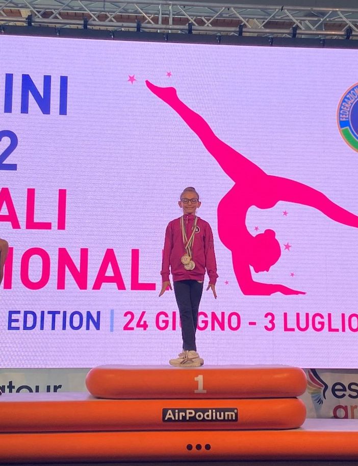 La giovanissima atleta sul gradino più alto del podio e, a fine articolo, ritratta con le tre medaglie vinte