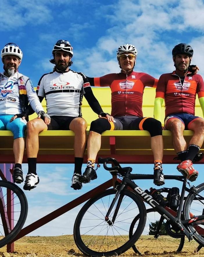 Cicloturisti in posa sulla panchina gigante di Ferrere