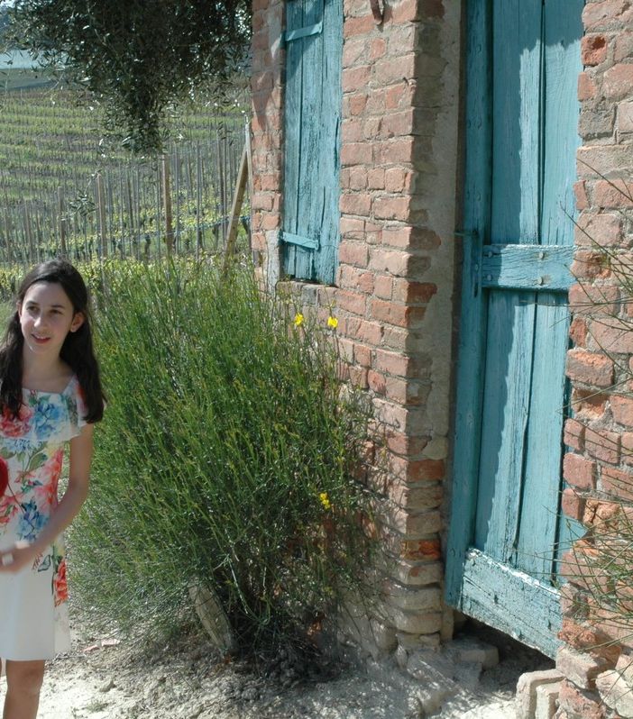 la giovane attrice Alice Borghetto tiene in mano il gomitolo di lana rossa che lanciato tra i filari scandisce il racconto delle tradizioni, di generazione in generazione