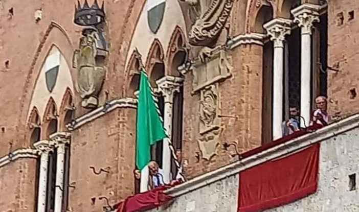 La bandiera verde esposta alla trifora del Palazzo Pubblico senese (foto riprodotta per gentile concessione del blog &quot;Brontolo dice la sua&quot;)