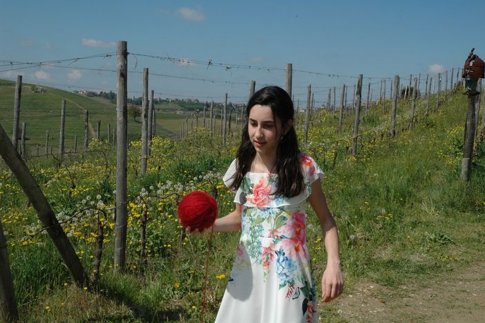 La giovane attrice Alice Borghetto con il gomitolo di lana rossa che scandisce il racconto La giovane attrice Alice Borghetto con il gomitolo di lana rossa che scandisce il racconto
