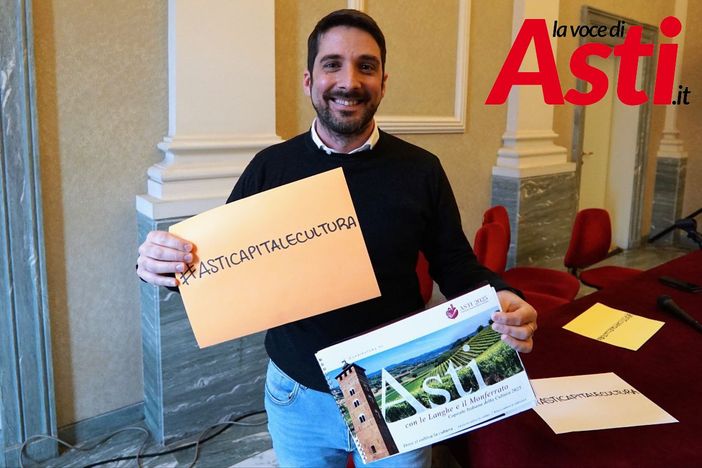 Nell'immagine (ph. Efrem Zanchettin), l'assessore Candelaresi ritratto mentre mostra uno degli hashtag associati alla candidatura astigiana