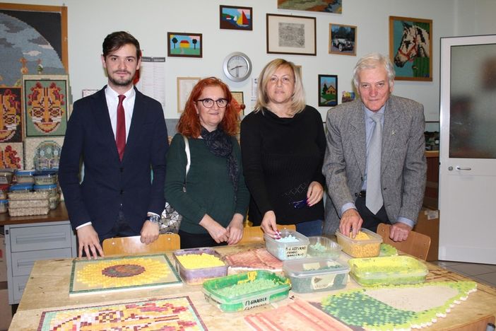 Angela Motta ritratta con i vertici Anffas nel laboratorio del mosaico