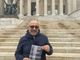 Larganà ritratto con una copia del suo romanzo d'esordio