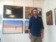 Il fotografo Gregory Pepper ritratto con alle spalle alcuni suoi scatti