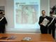 Il comandante Breda con il calendario 2019 e, sullo sfondo, la proiezione dello scatto inserito nella versione da tavolo