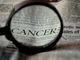 Lente di ingrandimento sulla parola cancro sulla pagina di un giornale
