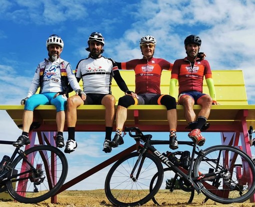 Cicloturisti in posa sulla panchina gigante di Ferrere